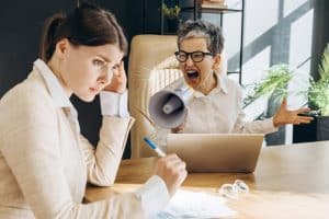 Chefin gibt ihrer Mitarbeiterin Feedback und schreit sie an