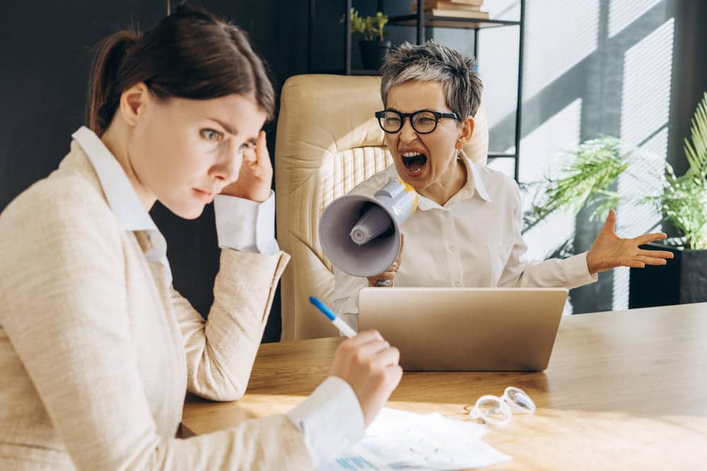 Chefin gibt ihrer Mitarbeiterin Feedback und schreit sie an