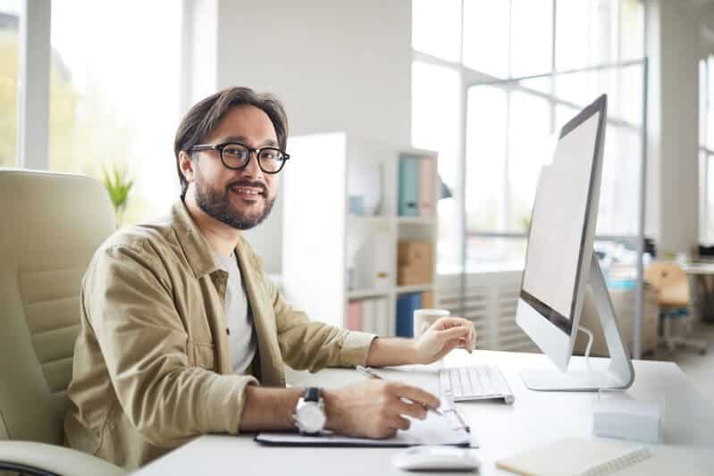 Mann der am Schreibtisch sitzt und am Computer arbeitet