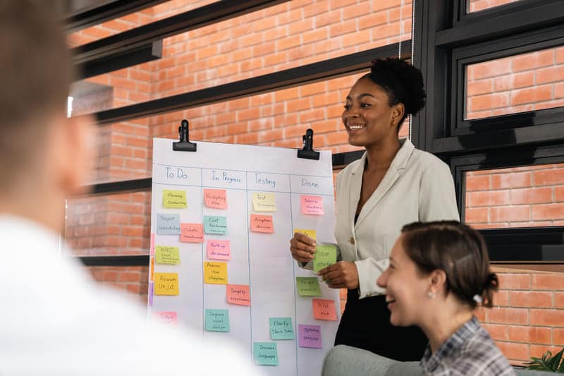 Frau steht an einem Scrum Board in einem Meeting