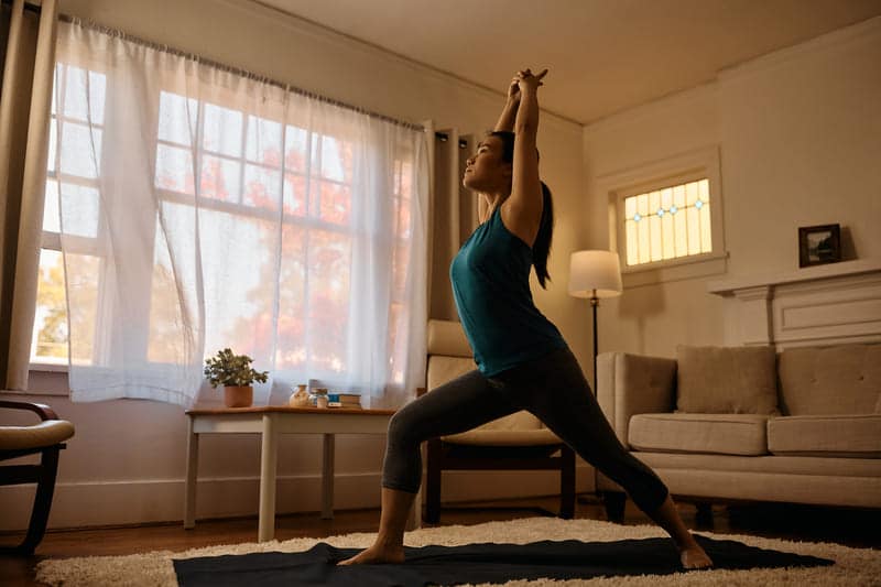 Frau macht Yoga in einem Wohnzimmer