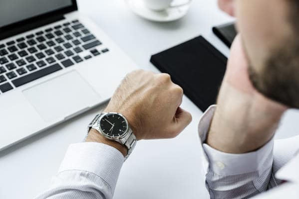 Armbanduhr eines Mannes im Büro zeigt die Arbeitszeit an