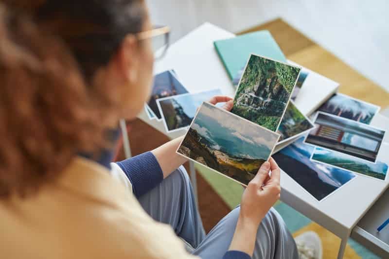 Eine Frau hält Postkarten in den Händen aus dem Urlaub und betrachtet diese