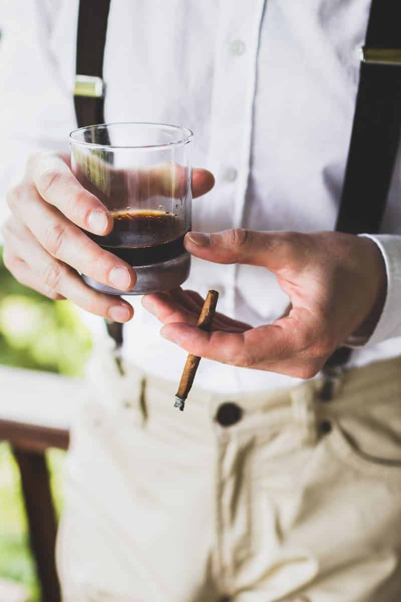 Mann hält ein GLass mit Kaffee und macht eine Raucherpause mit einer Zigarette in der Hand