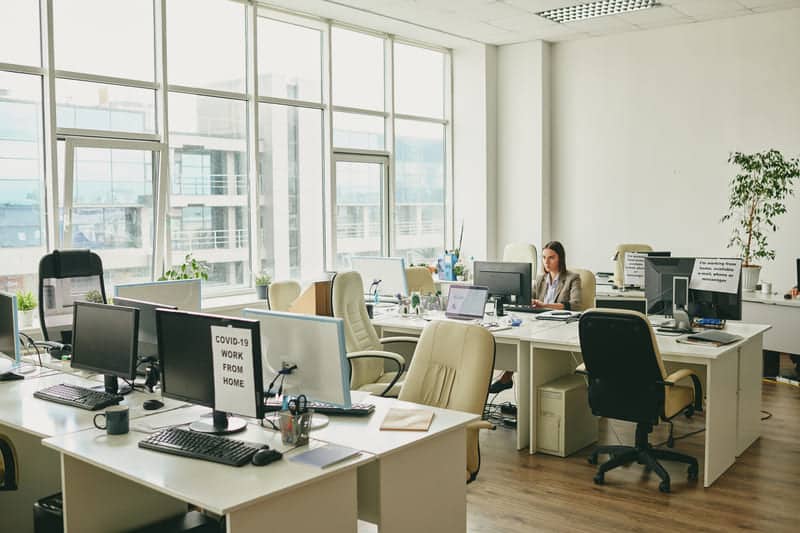 Ein leeres Büro mit vielen Schreibtischen und nur einer Mitarbeiterin